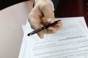 male hand in a business suit holding a pen and preparing to sign a title insurance contract