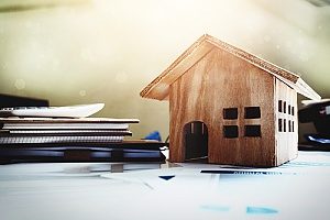 a wooden house and paperwork representing What Does Title Insurance Cover?
