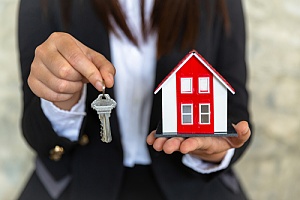 Key to home and small home being held 