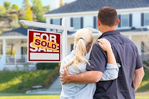 couple standing outside their home that is sold