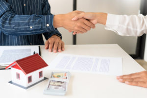 realtor and homebuyer shake hands after homebuyer exudes commitment to buy title insurance