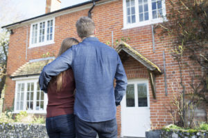 couple stand in front of their new home after settling owners title insurance dispute