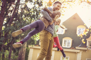 father plays with his daughters after securing owner’s title insurance for the house