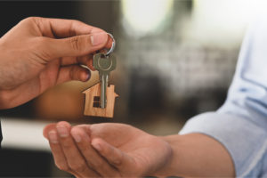 realtor hands house key to homeowner after the homeowner bought a title insurance policy