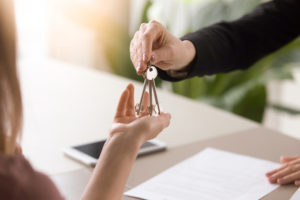 broker hands keys to new homeowner after homeowner signed the owners title insurance contract