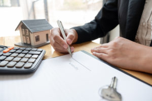 calculator sits on top of the document the mortgage broker is signing