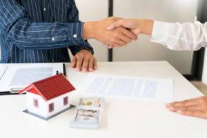real estate settlement company employee and homeowner shake hands after coming to an agreement regarding sale of home