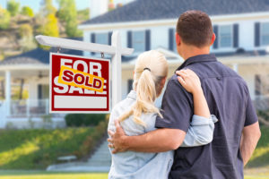 the first time home buyers stand in front of their home