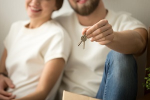 new home owners couple holding house keys after knowing how long does title insurance last