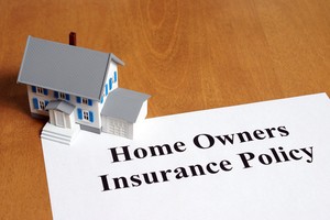 Homeowners insurance policy written on blank white paper placed under 3d plastic house